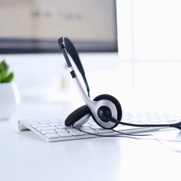 axvoice voip service review white office white desk and laptop keyboard with headset over  it monitor in the background